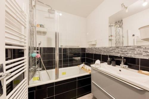 ein Bad mit einer Badewanne, einem Waschbecken und einer Dusche in der Unterkunft Superbe appartement 5P in Châtillon