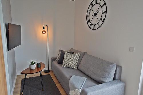 salon z kanapą i zegarem na ścianie w obiekcie Apartament West Wrocław / Parking Free we Wrocławiu