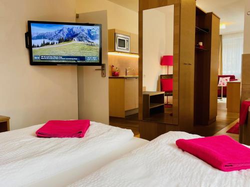 ein Hotelzimmer mit 2 Betten und einem Flachbild-TV in der Unterkunft Aparthotel Bergtraum in Mühlbach am Hochkönig