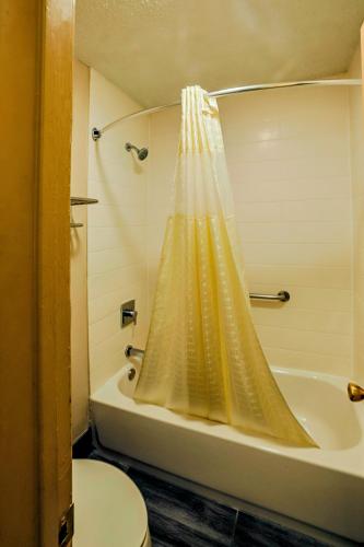 a bathroom with a shower curtain next to a toilet at Motel 6 Nacogdoches, TX in Nacogdoches