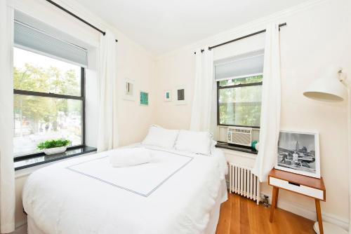 a white bedroom with a large bed and two windows at Three Bedroom West Village Townhouse in New York