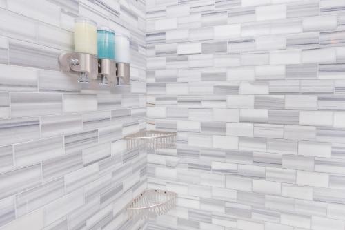 La salle de bains est revêtue de carrelage blanc et gris. dans l'établissement Three Bedroom West Village Townhouse, à New York