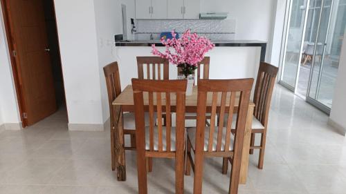 una mesa de madera con sillas y un jarrón de flores. en Plateia - Casa de Playa en Zorritos en Bocapán
