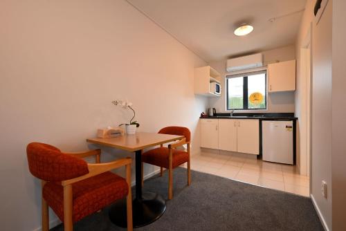 uma cozinha com mesa e cadeiras num quarto em Riccarton Mall Motel em Christchurch