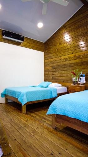two beds in a room with wooden walls at Hospedaje Yarisnori in Bocas del Toro