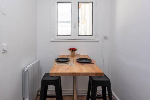 une table en bois avec deux chaises noires et une fenêtre dans l'établissement La Teranga B avec salle de sport, à Rouen