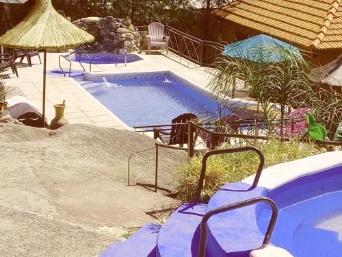ein kleiner Pool mit einem Stuhl und einem Sonnenschirm in der Unterkunft Cabañas Layken in Villa Carlos Paz