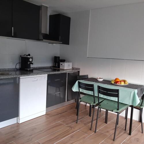 a kitchen with a table with chairs and a bowl of fruit at Casa do Loureiro - Apartamento in Paradela