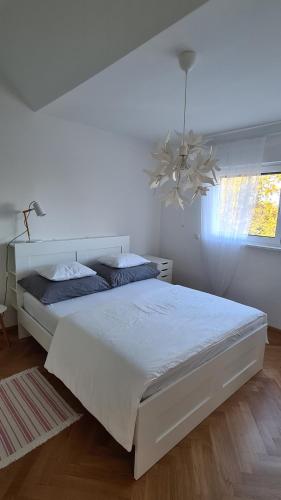 a white bedroom with a white bed and a chandelier at TOP Apartments Kaiserebersdorf in Vienna