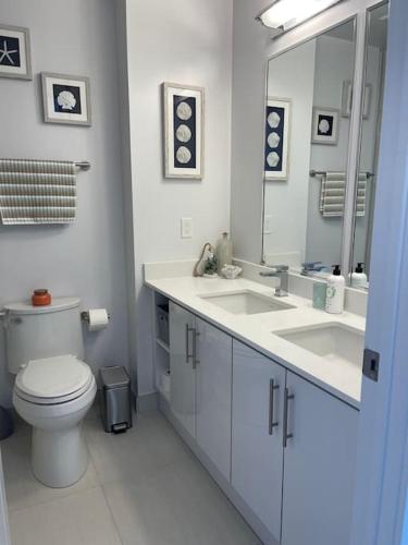 a bathroom with a toilet and two sinks and a mirror at 2 bedroom 2 bath Aquarius, Friday Harbour, Innisfil, Barrie in Innisfil