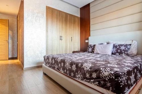 a bedroom with a bed with a wooden wall at Luxury Apartment Les perles de Marrakech in Marrakech