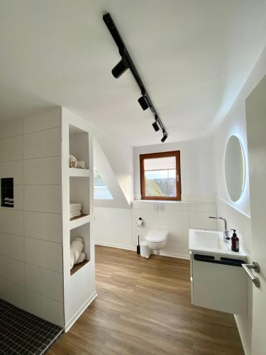 a white bathroom with a sink and a toilet at Ferienwohnung am Bollrich in Goslar