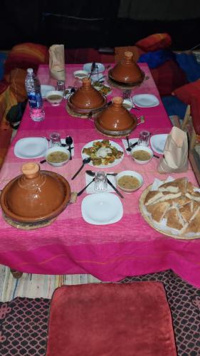 a table with plates of food on a pink table cloth at Gambi Camp in Hassilabied