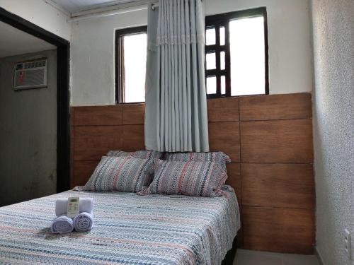 um quarto com uma cama com uma cabeceira de madeira em Um Paraíso no fim da rua em Barra de São Miguel