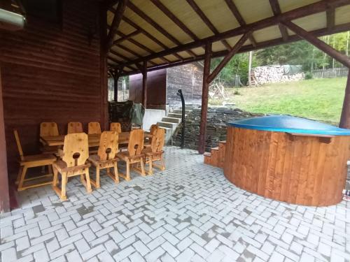 einen Holztisch und Stühle in einem Pavillon mit einem Tisch und einem Tisch in der Unterkunft Patakvölgye Vendégház in Izvoare