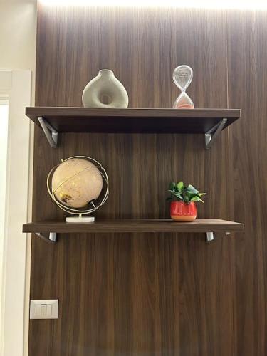 two shelves with vases and a clock on a wooden wall at ALBARI HOUSE in Bologna