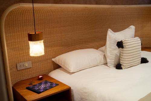a bed with white pillows and a table with a lamp at Casa Antonieta in Oaxaca City