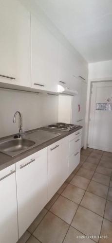 a kitchen with white cabinets and a sink at Vacances relax à Bredene in Bredene