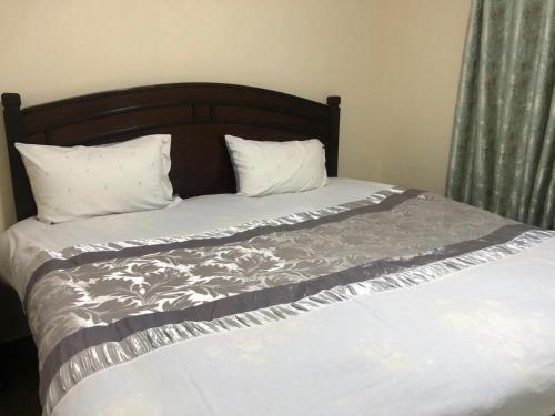 a bed with a wooden headboard and two pillows at the botanical bliss 1 bedroom in Nairobi