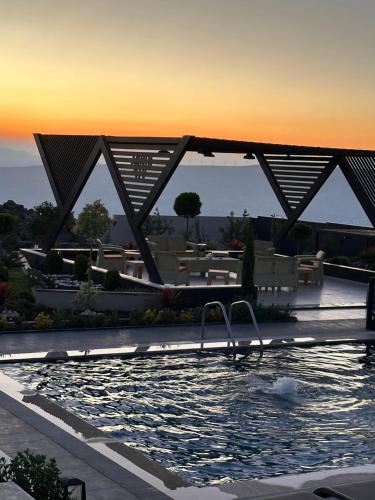 a swimming pool with chairs and a sunset in the background at Kinda vip in Al Mashāriqah