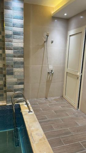 a bathroom with a tub and a shower with a sink at درة العروس فيلا فاخره بمسبح داخلي in Durat  Alarous