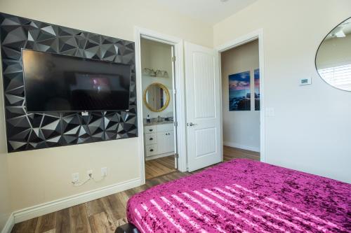 a bedroom with a pink bed and a flat screen tv at 3400 SqFt House W/40Ft Heated Pool/Spa- Strip View in Henderson