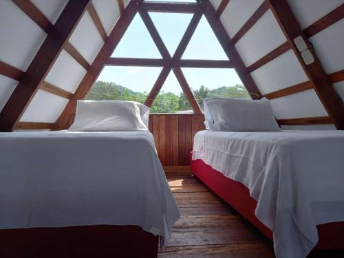 two beds in a room with a large window at Glamping RanchoEmilio in Villavicencio