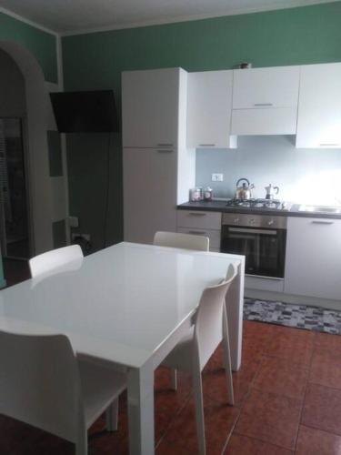 a white kitchen with a white table and chairs at Appartamento 4 - NEW in Comezzano