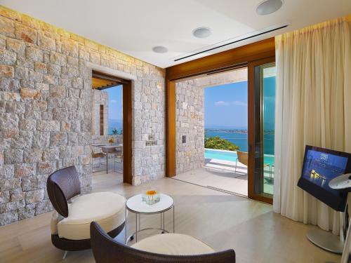 a living room with a tv and a stone wall at Nafplia Palace Hotel & Villas in Nafplio