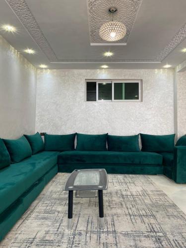 Appartement à louer 80 m² à Aourir - agadir في أورير: غرفة معيشة مع أريكة خضراء وطاولة