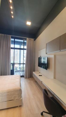 a bedroom with a bed and a desk with a television at Belíssimo Studio Perdizes in São Paulo