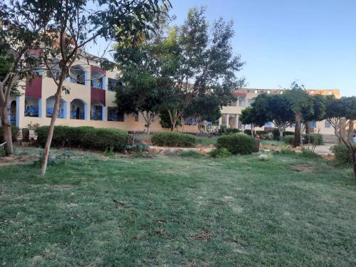 Bawati的住宿－Oasis Panorama Hotel，一座有树木的建筑,前面有一片田野
