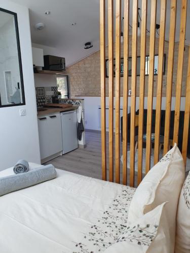 Cet appartement comprend une chambre avec un lit blanc et une cuisine. dans l'établissement Studio confort, charme & tranquilité, à Beaumont