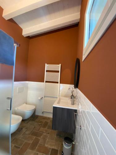 a bathroom with orange walls and a toilet and a sink at Fuoridicampo beige in Roncovetro