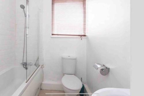 a white bathroom with a toilet and a bath tub at Seaside Property in Leigh-on-Sea