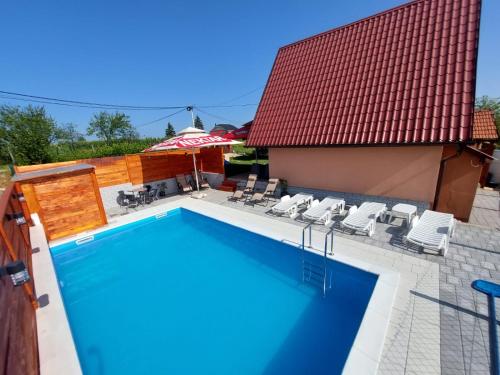 einen Pool mit Stühlen und einem Sonnenschirm in der Unterkunft Vikendica Krčmarice in Banja Luka