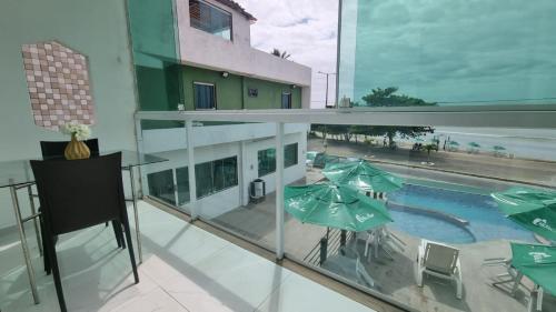 保利斯塔的住宿－Casamar Pousada，大楼内带游泳池和遮阳伞的阳台