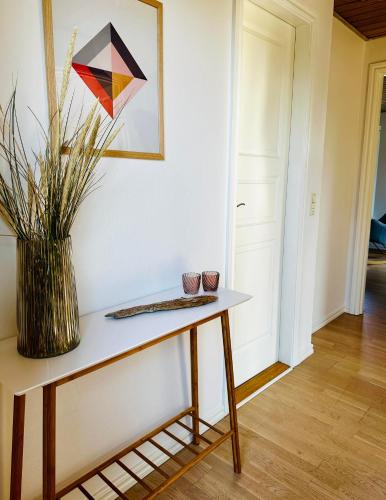 een tafel in een kamer met een vaas erop bij Skøn villalejlighed i Skagen med terrasse og tæt på centrum in Skagen
