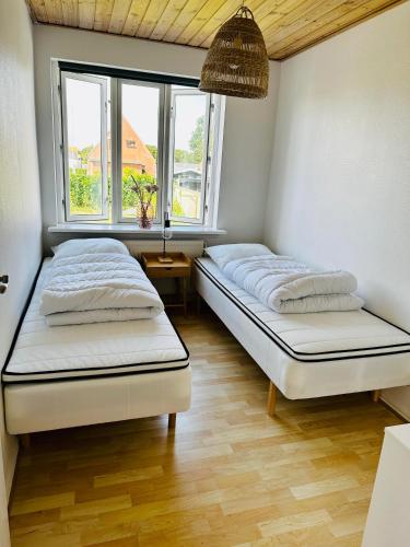 two beds in a room with two windows at Skøn villalejlighed i Skagen med terrasse og tæt på centrum in Skagen