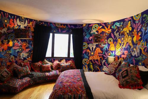 um quarto com uma parede colorida, uma cama e almofadas. em The Tower of Alebrijes in San Angel Inn em Cidade do México