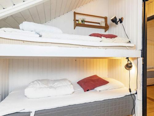 two bunk beds with white sheets and red pillows on them at Holiday home Tranekær XVIII in Tranekær