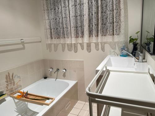 La salle de bains blanche est pourvue d'une baignoire et d'un lavabo. dans l'établissement Macyland, à Woollamia