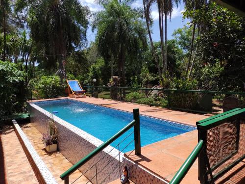 a swimming pool with a chair next to a fence at Quinta La calmita Iguazú in Puerto Iguazú