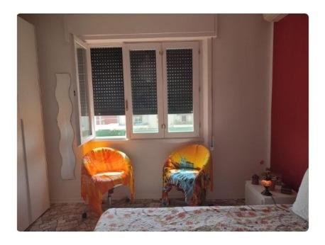 ヴィアレッジョにあるAppartamento Viareggioのベッドルーム1室(椅子2脚、窓付)