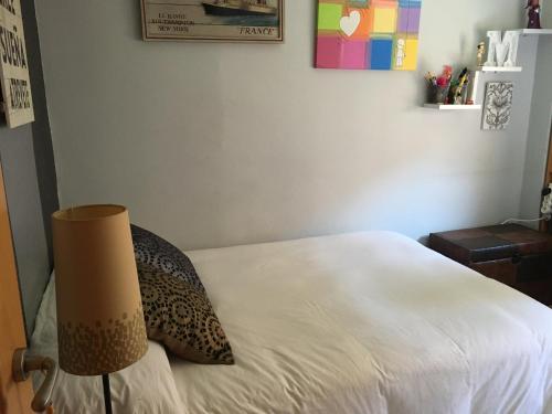 a bedroom with a white bed and a lamp at Habitación particular,baño compartido in Zaragoza
