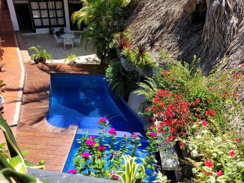 a swimming pool in a garden with flowers at Hostal Antawara Tayrona in El Zaino