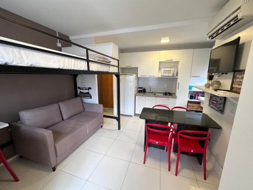 a living room with a couch and a table with red chairs at Flat para 4 pessoas em Boa Viagem com Piscina, Wifi 500Mbps, localizado a 350 metros da Praia in Recife