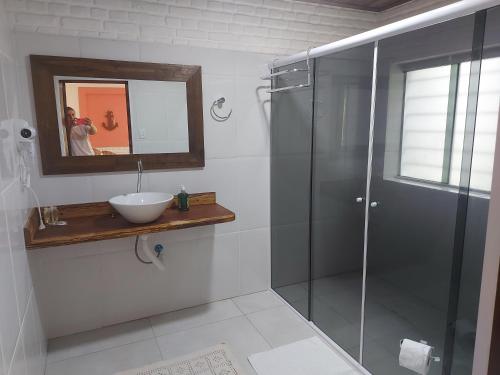 a bathroom with a glass shower and a sink at Pousada Ninhal das Garças in Ilha Comprida