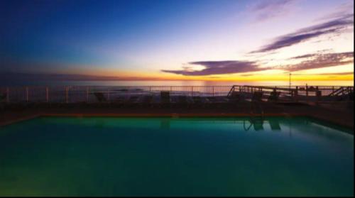 a swimming pool with a sunset in the background at New Listing: Water Views, Beach, West end near 30A in Panama City Beach