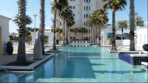 a swimming pool with palm trees and a building at New Listing: Water Views, Beach, West end near 30A in Panama City Beach